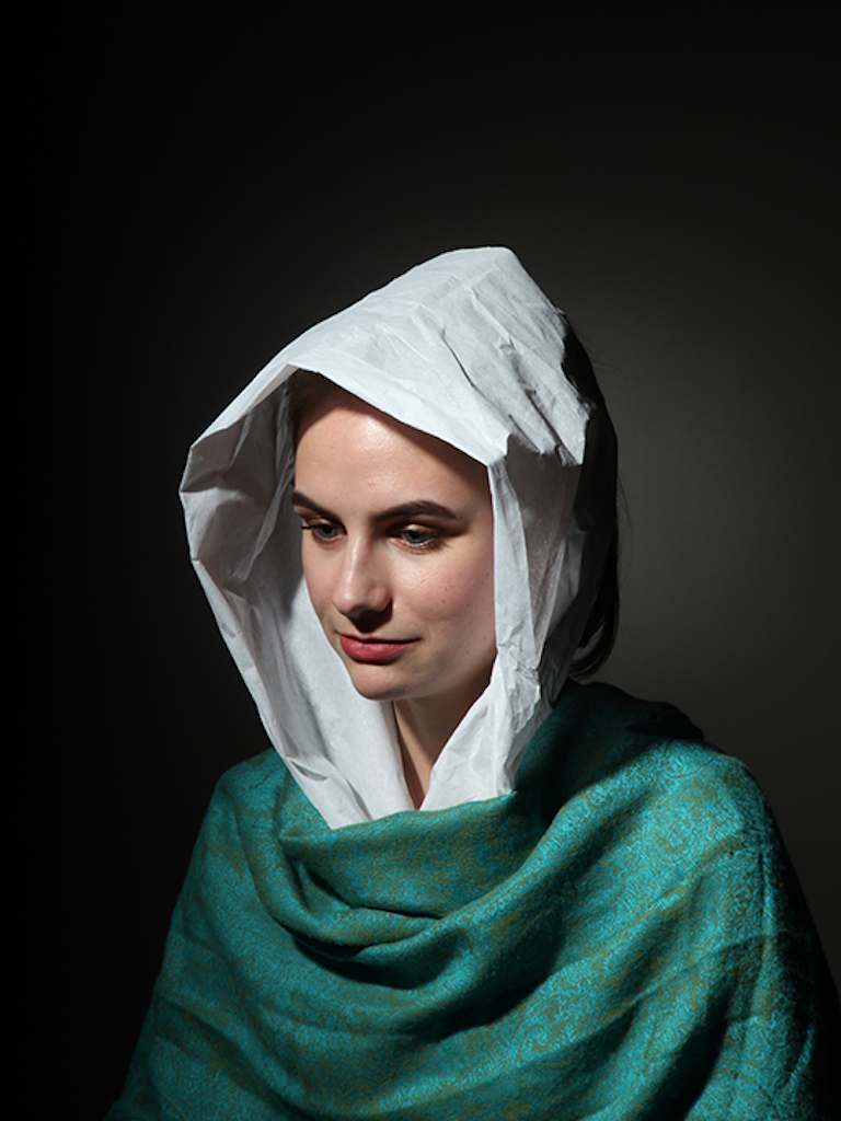 Color portrait of a white woman wearing a draped teal green top and a white hood.